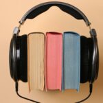 black corded headphones wrapped around a stack of colorful books