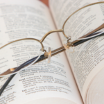 a photo of a pair of wire rimmed glasses resting on an open thesaurus