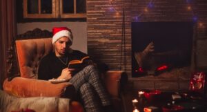 light-skinned man reading a book amidst Christmas decorations