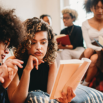 a photo of young women of color discussing books together
