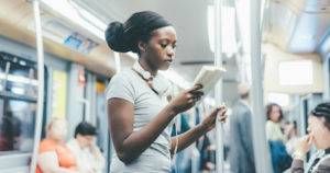 black woman reading book subway