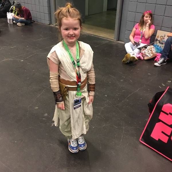 a very young girl dressed as Rey from Star Wars: The Force Awakens