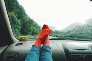Feet on car dashboard with forest background