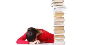 sad woman with head down next to book stack