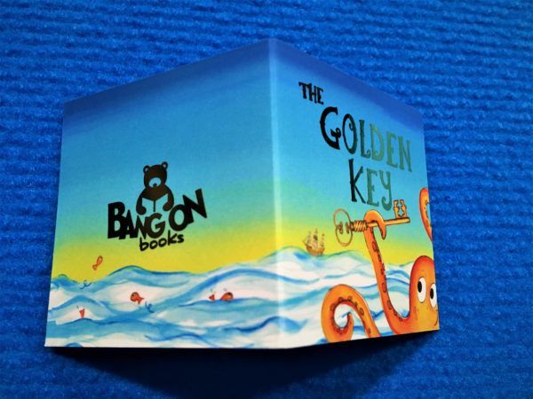 A tiny folded business card, showing a cartoon-style octopus and ocean, with the text "The Golden Key" and "Bangon Books"