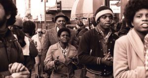 Members of Peoples Temple including Richard Parr, Wesley Johnson, Barbara Hickson, Ricky Johnson and Sandra Cobb attend an anti-eviction rally at the International Hotel, 848 Kearny Street in San Francisco, January 1977. Photo by Nancy Wong CC BY-SA 4.0