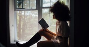 black woman reading in window home page feature