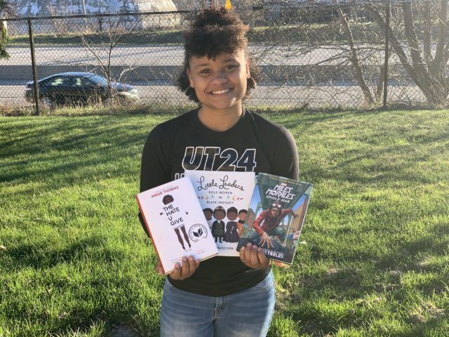 Nyesha Stone, with three books by authors of color. Photo used with permission of Stone. 