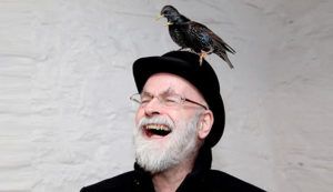 a photo of Terry Pratchett with a bird on his head