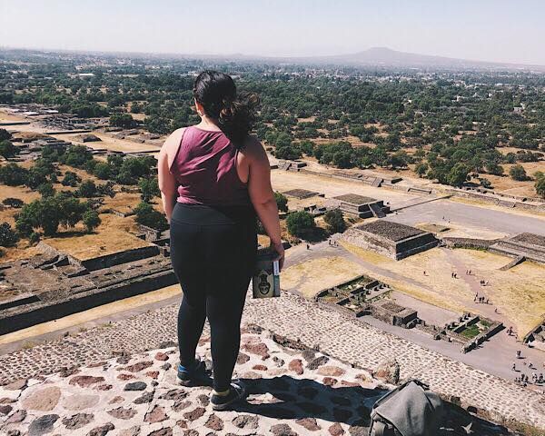 Me with a book looking over the view from the top of the Pyramid of the Sun in Teotihuacan