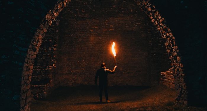 image of a man holding a torch in cave ruins https://unsplash.com/photos/5DIFvVwe6wk