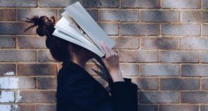 woman holding book over face