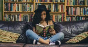 teen reading in front of a bookshelf