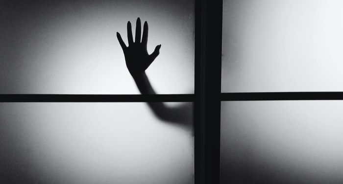 a silhouette of a hand pressed against a window