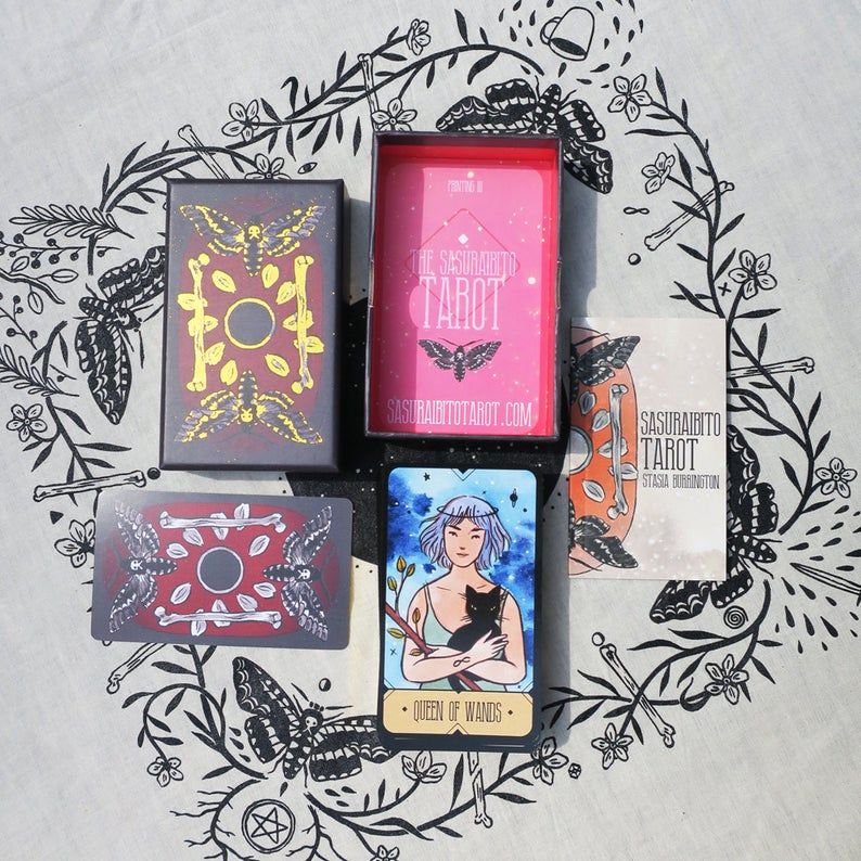Image of the box and the stack of cards of The Sasuraibito Tarot deck on an altar cloth