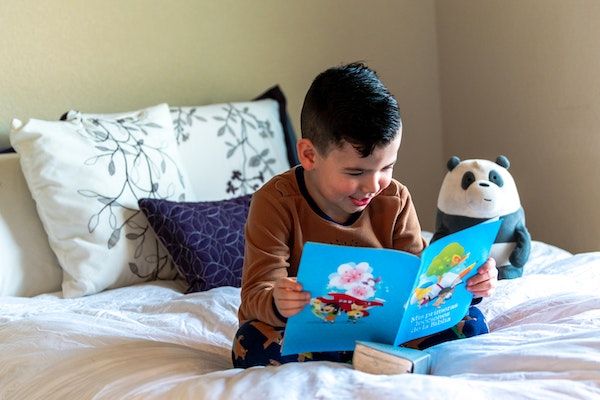 toddler reading on bed; Unsplash photo: https://unsplash.com/photos/Y9RFMB7Gb94