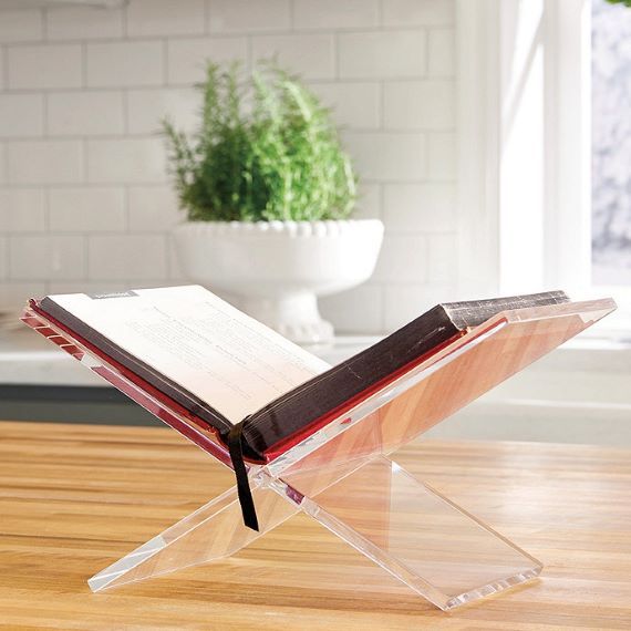 Clear, acrylic stand with an open book. Stand sits on a wooden table. Link: https://akamai-scene7.ballarddesigns.com/is/image/ballarddesigns/T_WithoutZoom?$w400$&$src=ballarddesigns/AS304_main