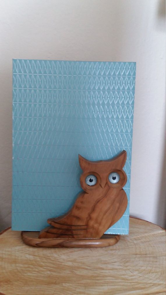 A book holder shaped like an owl sits on a desk. A blue book rests on the holder. Link: https://i.etsystatic.com/9184374/r/il/71ad29/1496295552/il_1140xN.1496295552_tdja.jpg