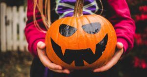 child holding a pumpkin jack o lantern for halloween
