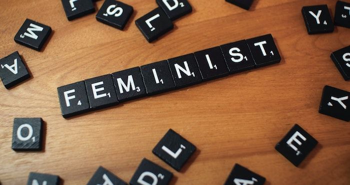 black and white Scrabble tiles spelling the word "feminist"