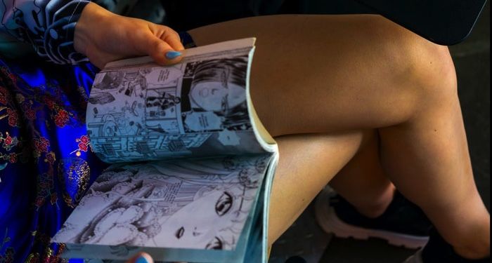 a person with crossed legs reading a comic book