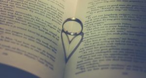 open book with ring inside casting a heart-shaped shadow