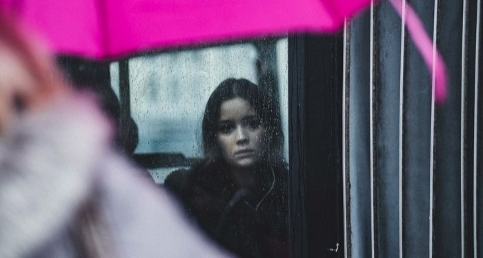 woman looking sadly out of rainy window