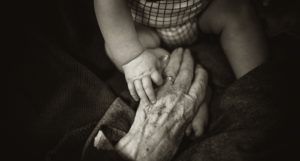 baby hand on top of older persons hand
