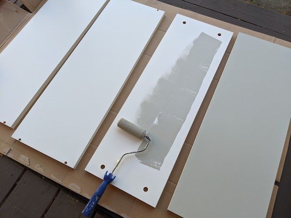 Photo showing the painting of primed bookcase pieces, courtesy of author