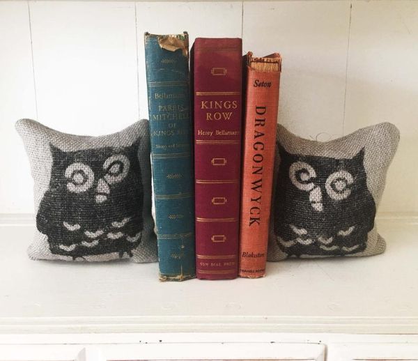 two burlap feedsack pillows with the image of an owl printed on them being used as bookends