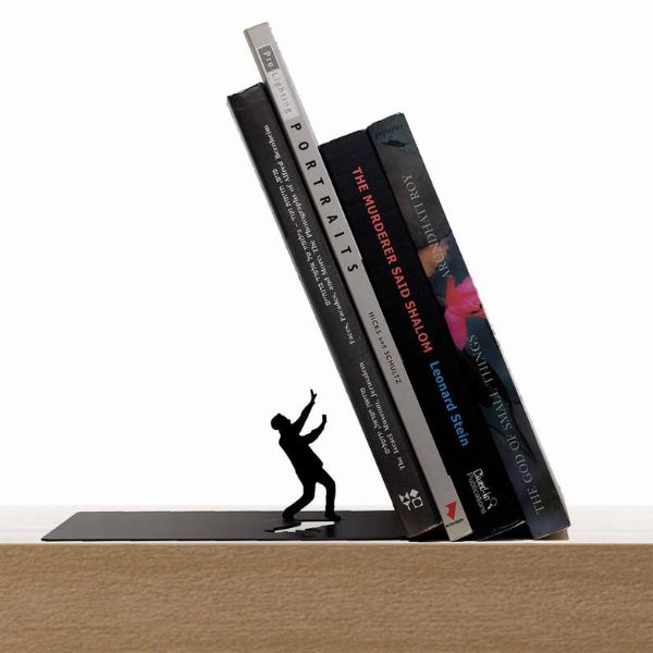 a metal silhouette of a man holding his arms up as it appears books are about to fall on him