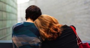 two people leaning on each other with their backs turned toward viewer