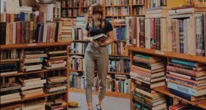woman holding books in bookstore