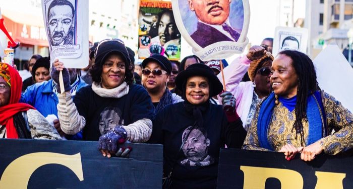 Black women holding Martin Luther King Jr signs at march for civil rights and Black history feature