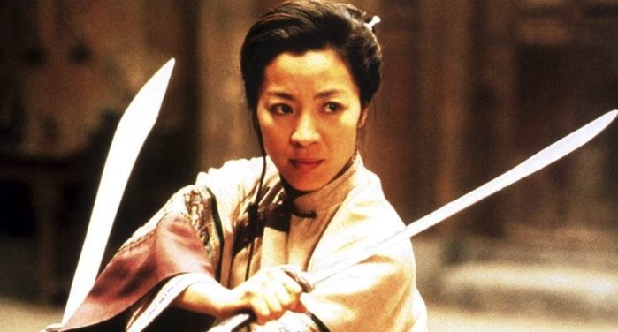 still image of Michelel Yeoh in Crouching Tiger Hidden Dragon; a woman in a defensive stance holding two swords https://www.imdb.com/title/tt0190332/mediaviewer/rm2623090432/