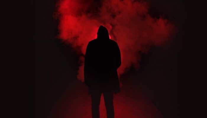 Menacing outline of a person standing in front of red smoke
