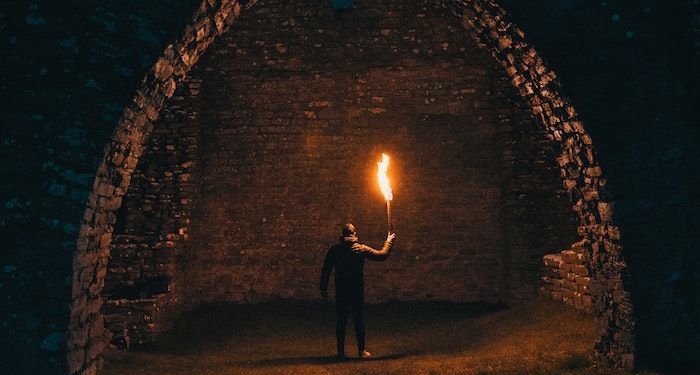 person holding torch in tunnel for horror fantasy feature