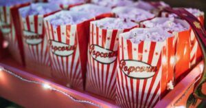 small colorful popcorn bags in a pink box with string lights for movies