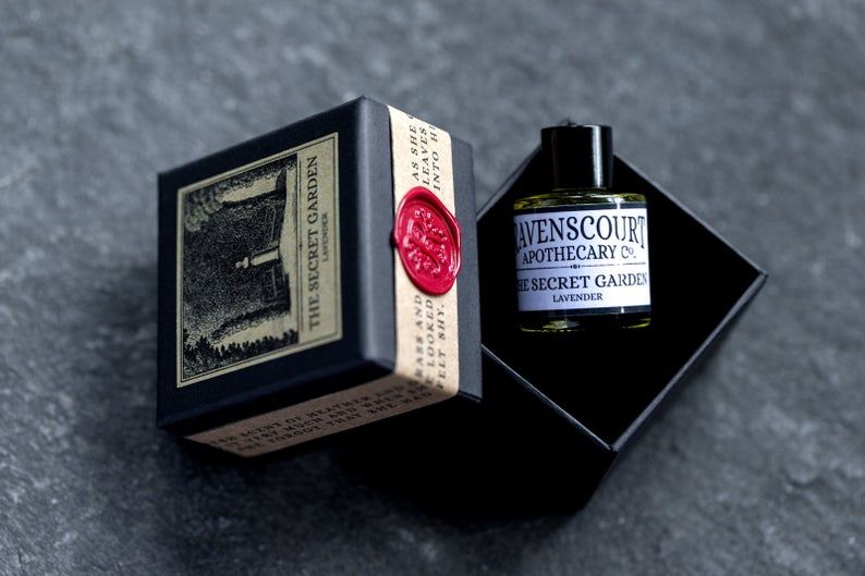 A perfume bottle labeled The Secret Garden sitting in a velvet box, with the box top tilted off to the side