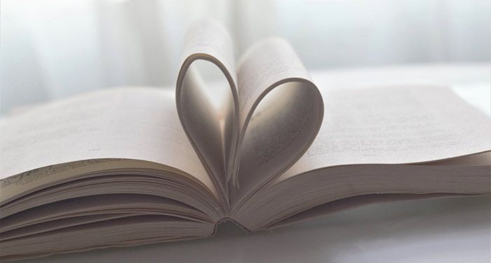 a photo of a book lying open on a table, with pages bent into the shape of a heart