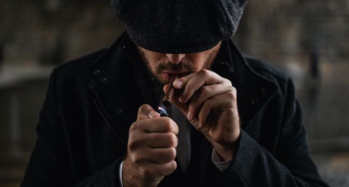image of a man in a black knit cap lighting a cigarette