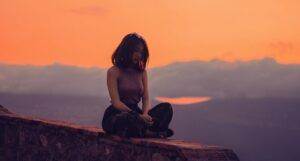 wellness feature of woman sitting on wall at sunset