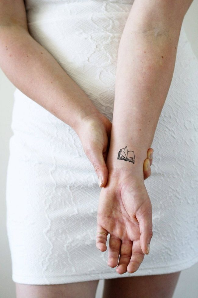 Image of a temporary tattoo of an open book with blank pages on a person’s outstretched wrist
