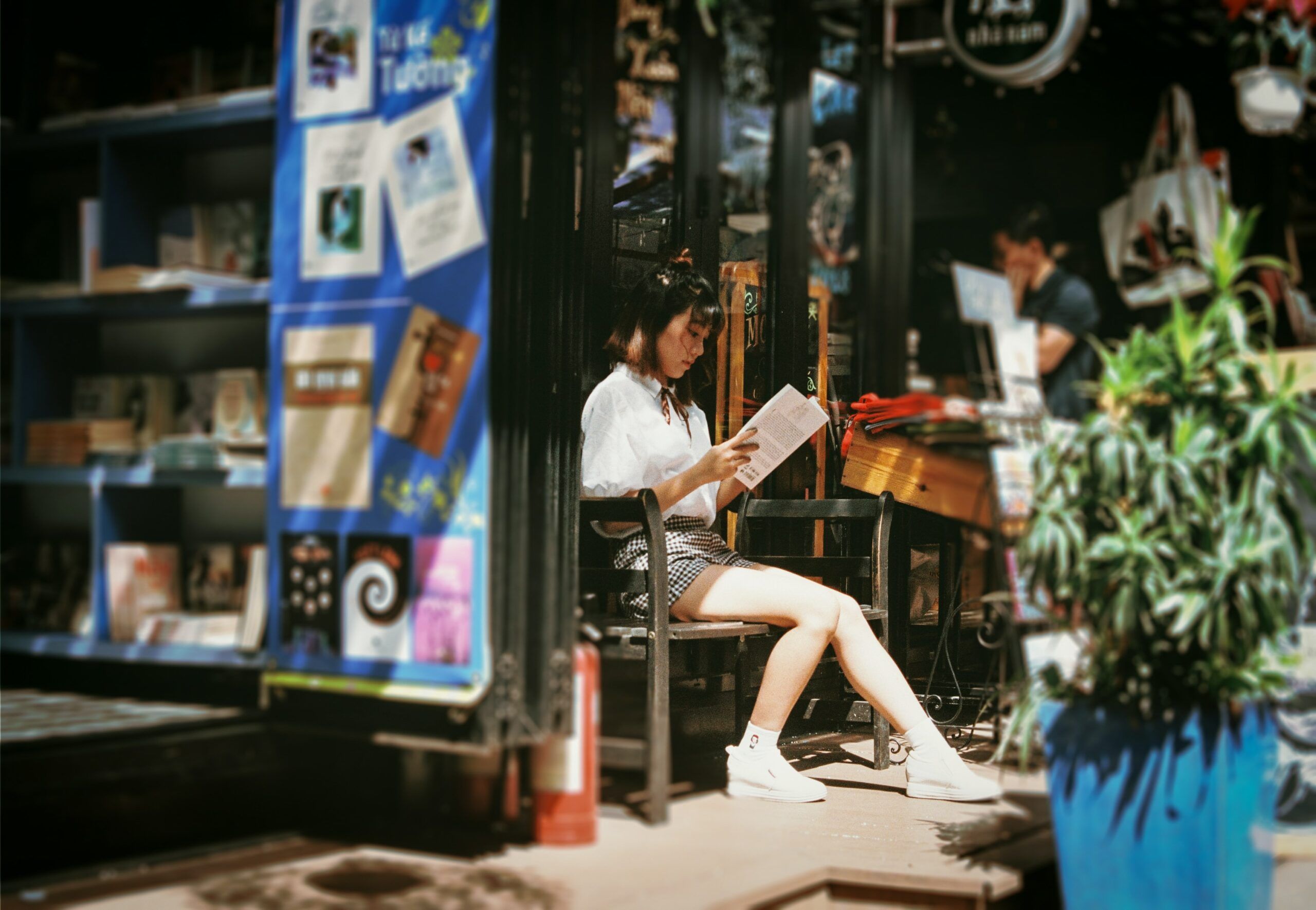 A woman is seen reading a book in front of a bookstore 