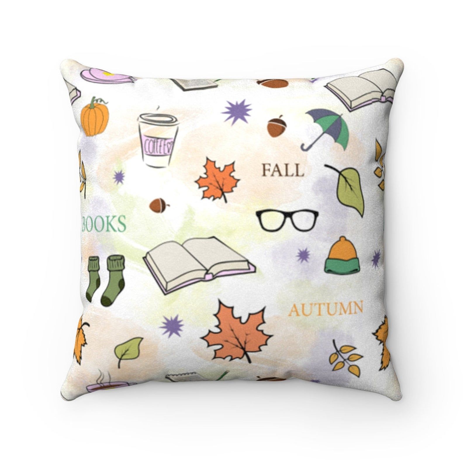 Image of a white throw pillow with fall images, including books, acorns, leaves, and cozy socks. 