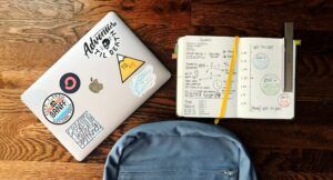 Image of backpack, notebook, and laptop on wood table