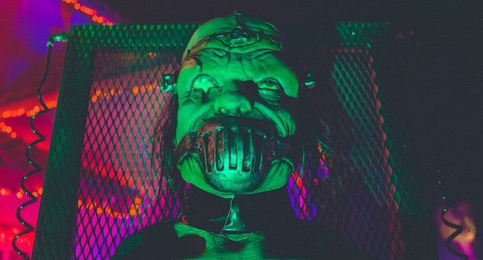 a scary masked figure in front of neon lights