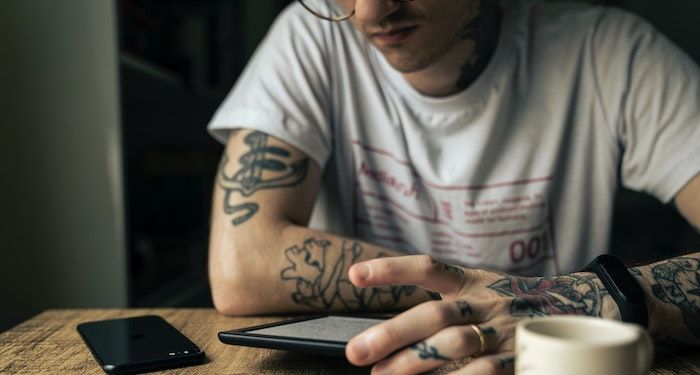 tattooed person reading ereader