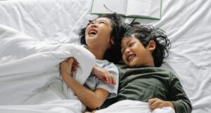 kids laughing in bed with book behind them