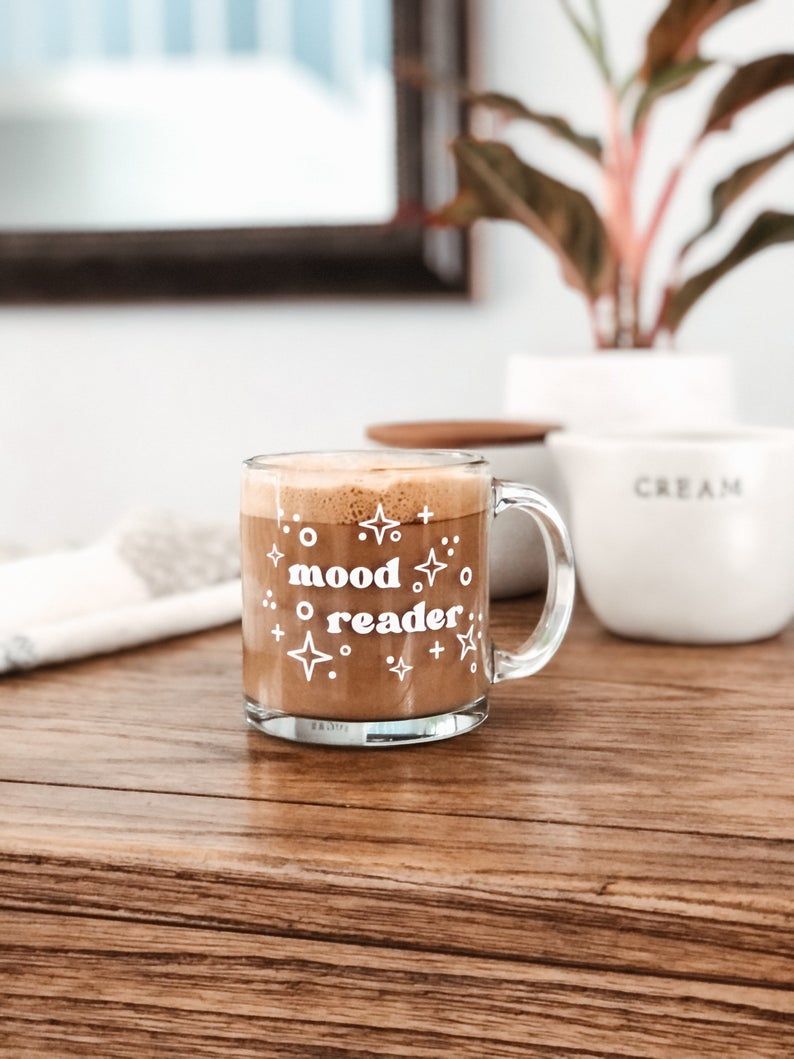 a glass mug with the words mood reader sitting on a brown table 
